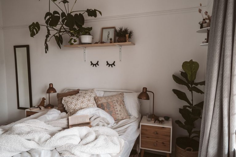 Cozy bedroom with warm light, plants, and a neatly made bed