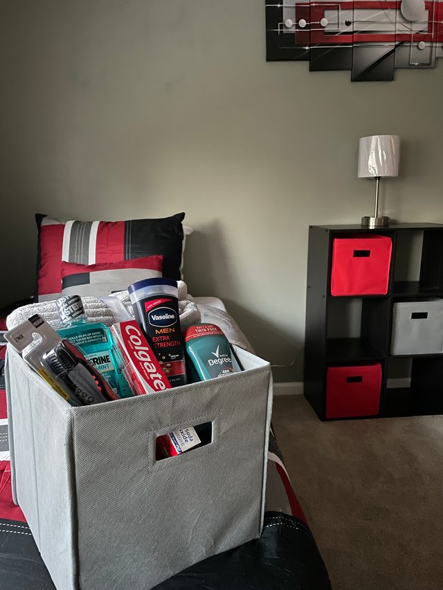 Welcome hygiene kit basket on a bed with red and black bedding