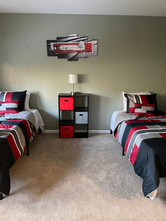 Furnished bedroom at Heart to Heart Homes with red and gray bedding and storage shelves